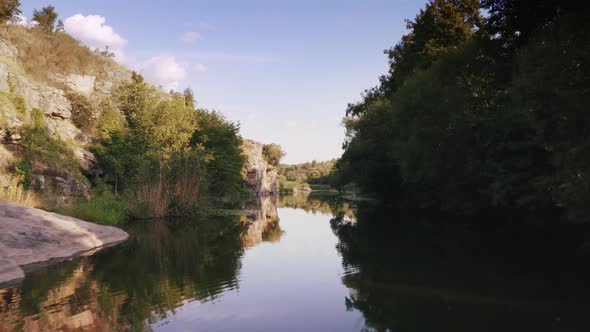 Aerial Shot with Drone Flying Close to the Water in Canyon During Sunny Day alt