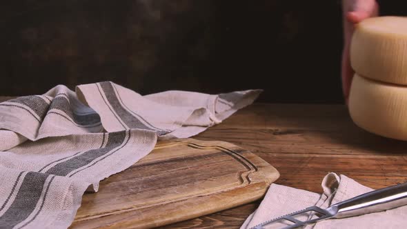 Women hands put wheels of  fresh homemade cheese on a wooden board close up alt