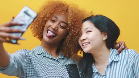 Crazy Young Multiracial Girl Friends or Lesbian Couple Making Funny Faces and Taking Selfie with alt