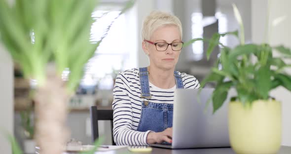 Mature woman with eyeglasses working at home on laptop