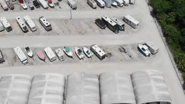 Forward drone aerial over boat and camper storage lot in South Florida.  Covered storage visible bel alt