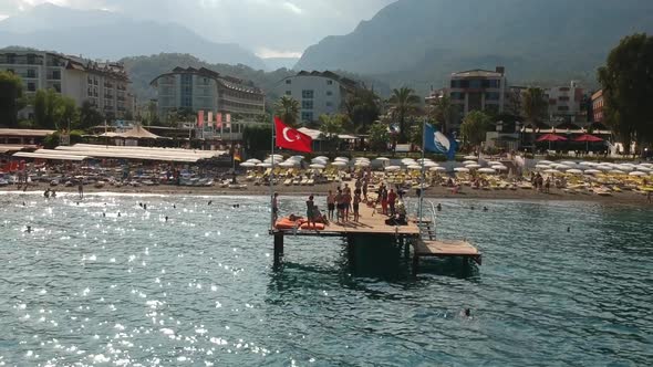 Aerial drone shot of people swimming and sunbathing on a pier at a hotel beach in Kemer, Turkey.