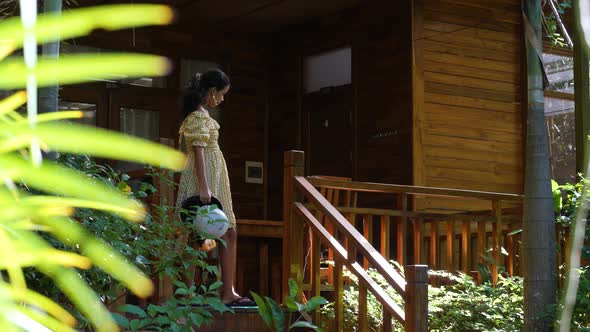 Young Woman Walking Down on the Stairs of a Veranda of a Wooden House alt