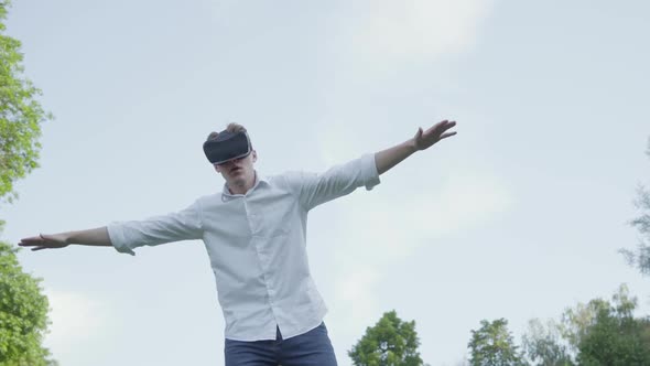 Young Man in Virtual Reality Headset Spread His Arms To the Side, Imitating the Flight of an alt