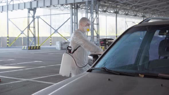 Man Dressed White Protective Overalls Spraying Vehicle Antibacterial Sanitizer Sprayer on Quarantine alt