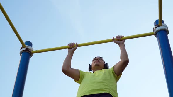 A Milineal Man with Headphones Pulls Himself Up on the Street alt