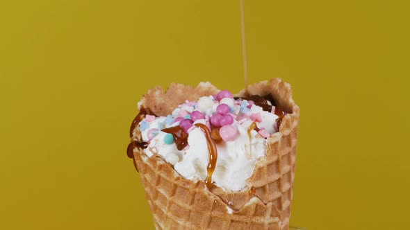 Close-up, Ice Cream Is Poured with Caramel in a Pastry Shop. Waffle Cone with Ice Cream Is Decorated
