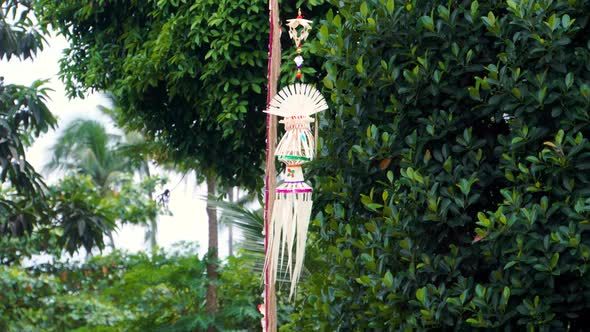 A Traditional Strawy Decoration of Balinese Hinduism Waving in Wind with Palm Trees in the