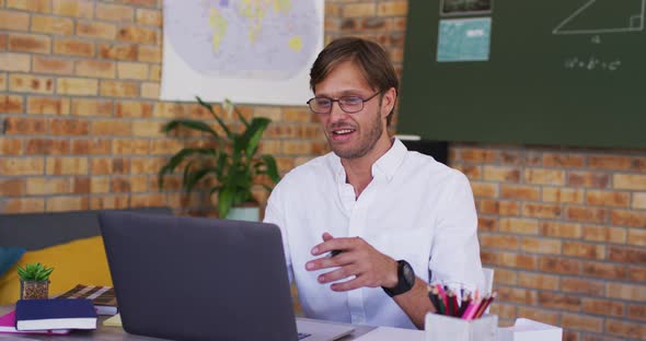Caucasian male teacher teaching on videocall on laptop in the classroom at school alt
