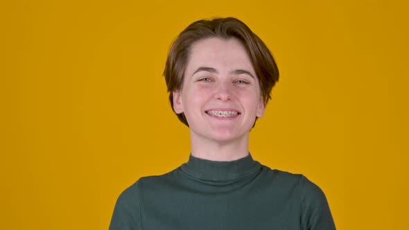 Positive young girl smiling and looking at the camera isolated on yellow background