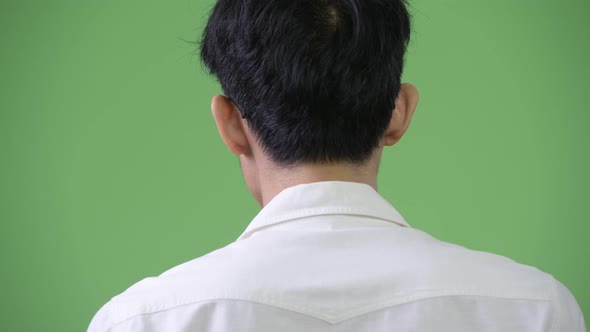 Young Curious Asian Businessman Looking Over the Shoulder alt
