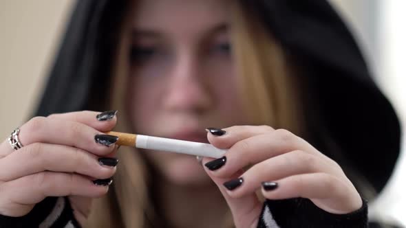 Teenage Girl Breaks a Cigarette