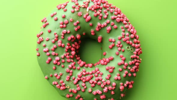 Fresh Green Glazed Ring Donut Covered By Pink Pastry Topping Rotating alt