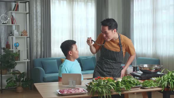 Asian Man Father And Little Child Son Cooking At Home, Food Tasting, Thumbs Up And Giving High Five alt