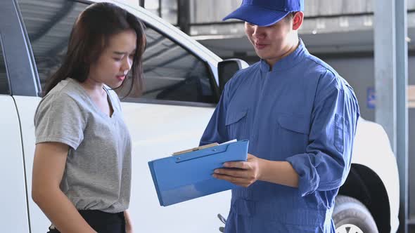 Asian car mechanic and female customer discussing to repairing and maintenance fixing automobile