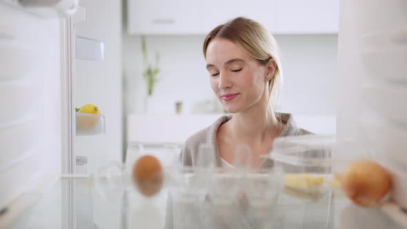 Woman opening the empty refrigerator and looking inside searching for something to eat