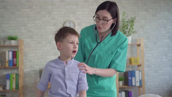 Pediatrician Listens with a Stethoscope To a Little Boy alt
