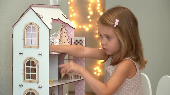 Girl Plays with Dollhouse with Toy Furniture