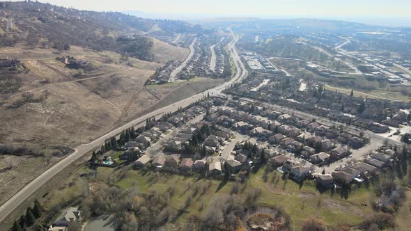 Wide angle drone birds eye footage over community of houses and streets, USA, with misty mountains i alt