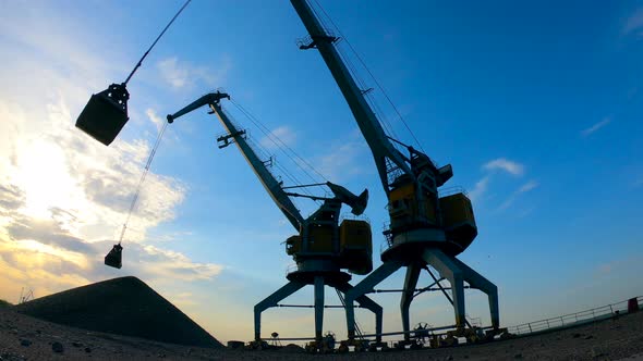 Gravel Is Getting Discharged By Two Loaders at Sunset alt