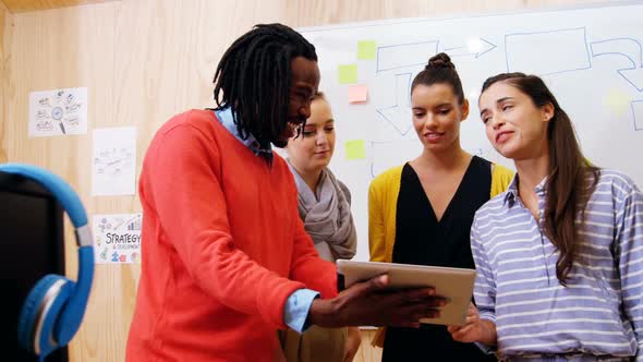 Business executives discussing over digital tablet in office alt