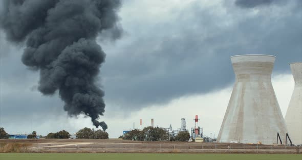 Accident in oil refinery - huge explosions and fireballs rising. Thick black smoke covers the sky. alt