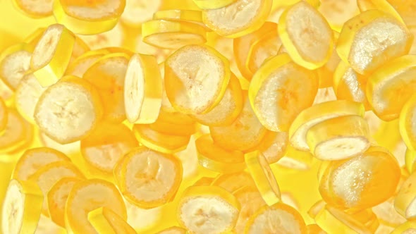 Super Slow Motion Shot of Fresh Banana Slices on Yellow Background Flying Towards Camera at 1000Fps alt