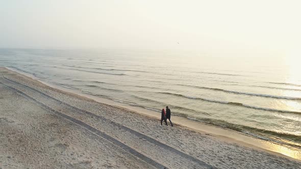Young Couple Walking on the Beach During Sunset