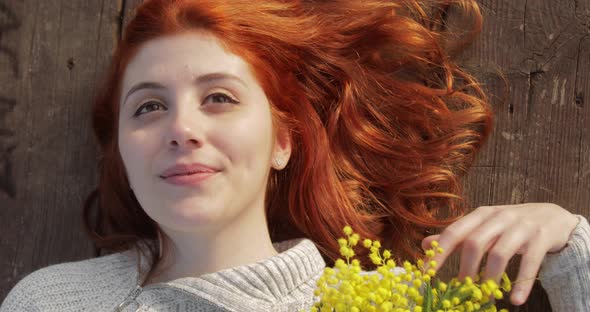 Young Girl on a Wooden Table with Mimosa Flowers for Women's Day alt