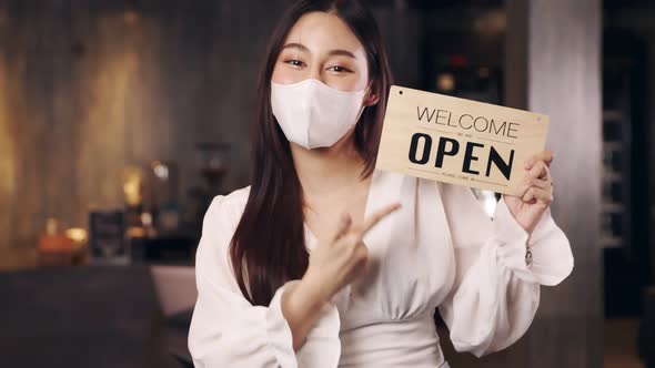 Business owner attractive young asian woman in apron hanging we're open sign alt