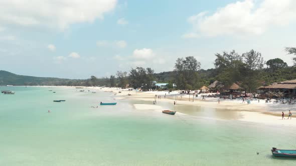 Populated shallow exotic shore with tourists and fishing boats in Saracen Bay in Koh Rong Sanloem alt