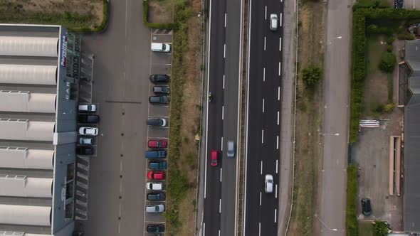 Highway road with buildings on sides, speeding vehicles, top down aerial view alt
