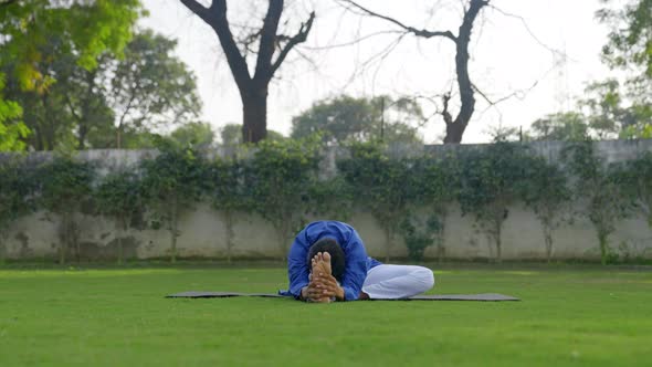 One leg forward bend yoga pose or Janusirasana is being done by an Indian man alt