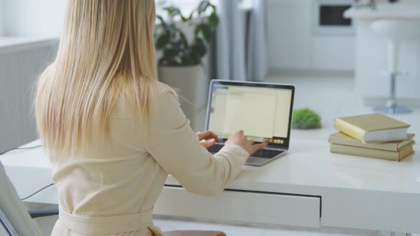 Young girl working at a laptop at home office. Young woman typing on laptop at the desk alt