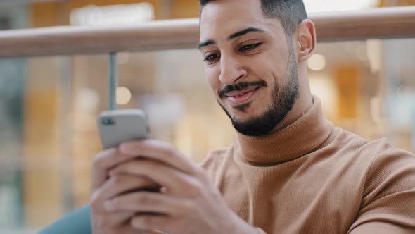 Closeup Young Arab Guy Holding Phone Looking at Screen Smartphone Smiling Receive Nice Email Message alt