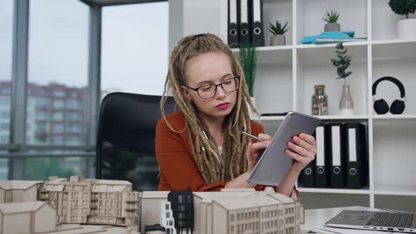 Female Architect with Dreadlocks Working with i-pad and Constructed Model alt