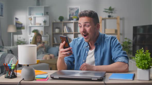 Couple Winners Hold Smartphone Feel Amazed Overjoyed with Mobile Online Bet Bid App Game Win alt