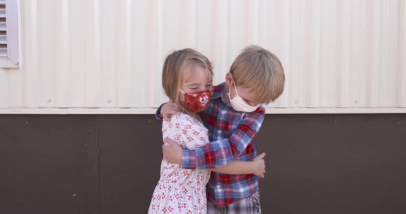 Two little kids hugging each other while wearing masks alt