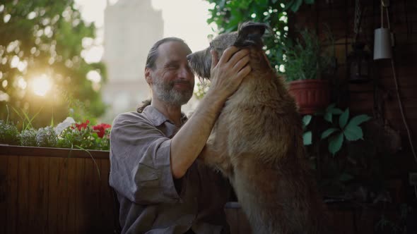 A Handsome Gentle Man Stroking His Shaggy Dog While Sitting on an Open Terrace