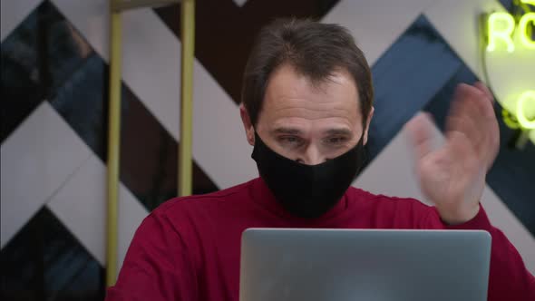 Handsome Middleaged Man Messaging and Chatting Sitting in Cafe with Laptop