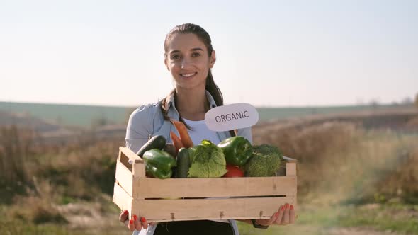 Girl Holding Box Of Vegetables. alt