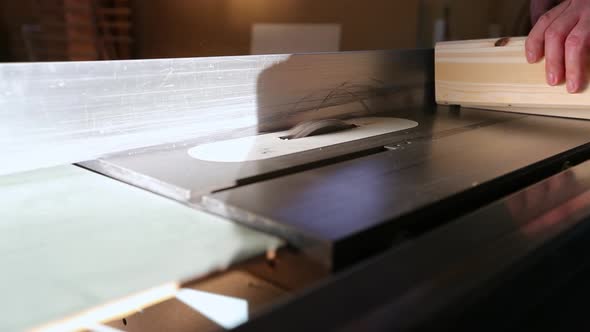 A craftsman starts up a table saw and cuts a groove in piece of wood using a dado set in slow motion alt