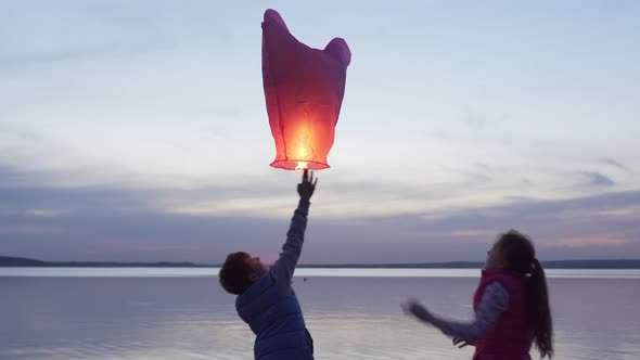 Happy Children Launch Sky Lantern By Sea at Sunset