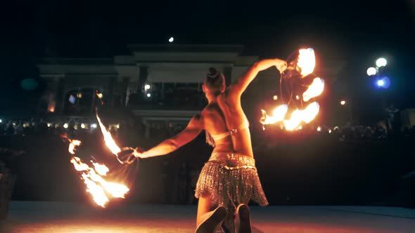 Sexy woman beautifully moves her body with burning fans in her hands