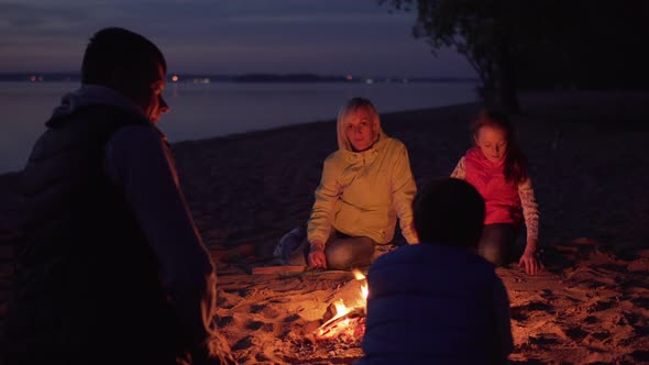 Father Stroking Son on Head By Campfire During Family Hike on Beach