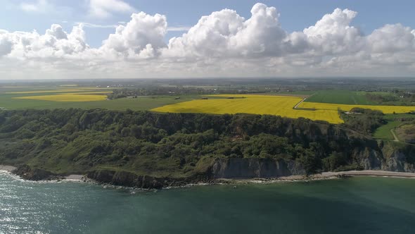 Panoramic drone view of Longues sur Mer sea cliff on sunny day. Aerial flying backwards alt