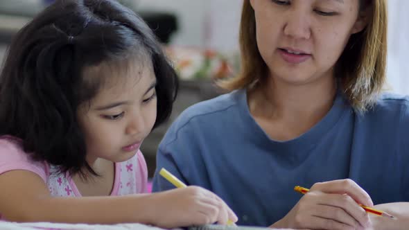 Close up shot Little Asian girl with mother doing homework in the bed room alt