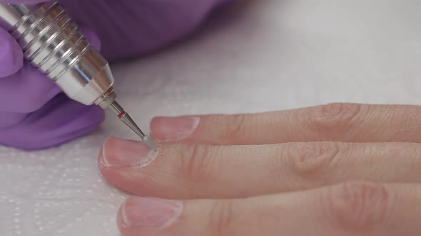 Young Woman Removes Gel Shellac Polish From Nails Using Manicure Machine, Close Up Shot