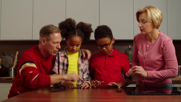 Loving Grandparents Teaching Dominoes Game to Multiracial Kids at Home alt
