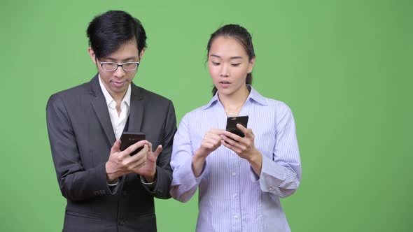 Young Asian Business Couple Using Phone Together